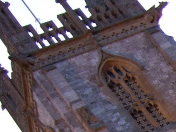 Blurry image of a church tower with architectural details, illustrating the low image quality.