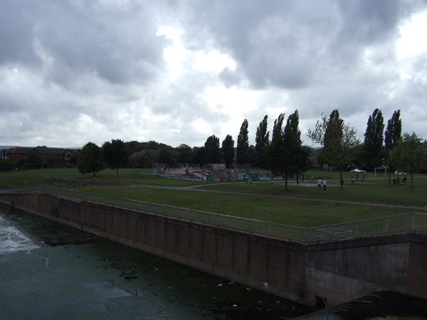 Photo taken with Fujifilm Finepix F30 showing an overcast sky above a public park with trees, a walking path, and a canal in the foreground.