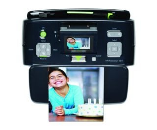 HP Photosmart A618 compact photo printer with a sample printed photo of a smiling child at a birthday party coming out of the printer tray. The printer's control panel is visible with options for layout, zoom, photo fix, and various other settings.
