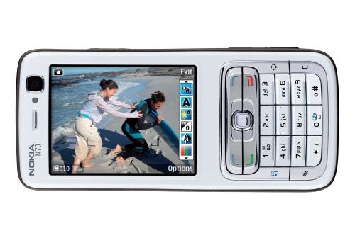 White Nokia N73 mobile phone with a horizontal screen displaying a photo of two children playing, surrounded by a standard keypad on the right, with menu and call buttons, and a navigation joystick in the center.