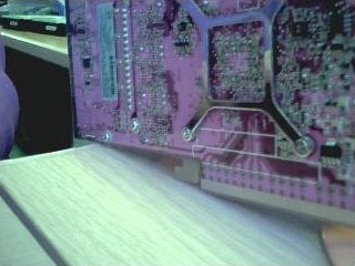 Close-up view of a purple circuit board, which may be part of the internal components of an MSI StarCam Clip, on a light-colored table with a blurred background.