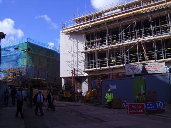 This image could represent a sample photo taken by a BenQ DC C1000 10-Megapixel Compact Camera, showcasing its capability to capture construction site scenes during daylight with people walking by, scaffolding in view, and signage indicating road closure. The image quality indicates good resolution and daylight capture, a typical example of the camera's outdoor performance.