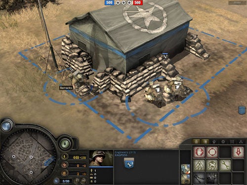 Screenshot of gameplay from Company of Heroes showing a barracks building with defensive sandbags and a user interface displaying in-game resources, minimap, and unit options.