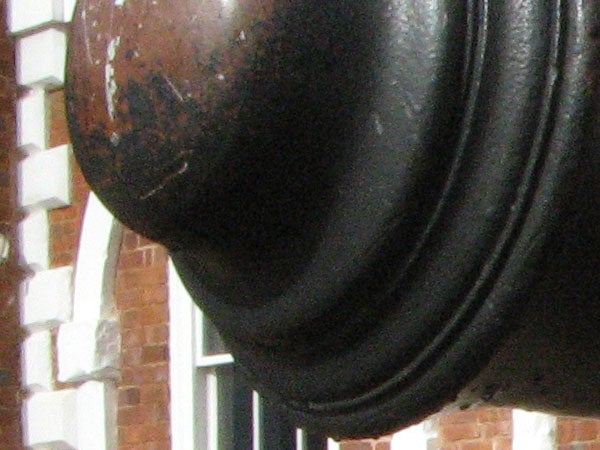 Close-up image of a worn-looking object with a blurry brick building in the background, likely taken with a Canon PowerShot A710 IS camera to demonstrate its macro photography capabilities.