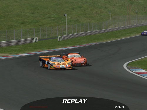 A screenshot from a racing game showing two virtual racing cars closely competing on a racetrack, with one orange and one yellow car, and an overlay indicating 'REPLAY' at the bottom with a time counter.