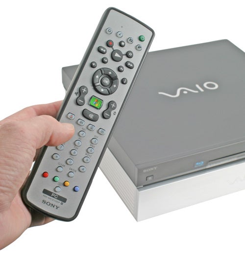 A hand holding a Sony Vaio remote control in front of the Sony Vaio VGX-XL202 Media Center PC with a visible Blu-ray Drive slot.