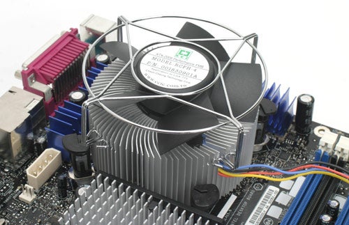 Intel Core 2 Extreme QX6700 processor with aluminum heatsink and fan mounted on a motherboard with RAM slots and peripheral ports visible.