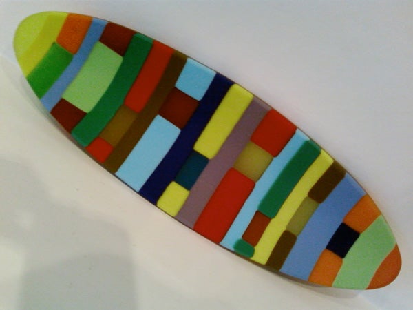 Image of a colorful mosaic pattern surfboard on a white background.