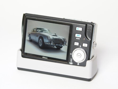 Nikon Coolpix S7c digital camera on a white background with a photo of a classic car displayed on its LCD screen.