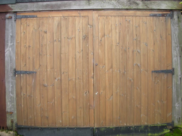 The image displays a set of wooden double garage doors with black metal hinges, not directly related to Nikon Coolpix S7c or a product review of it.