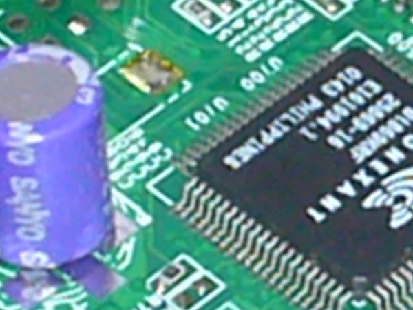 Close-up of an electronic circuit board featuring various components, including a Samsung chip, capacitors, and traces. The focus is slightly blurred, and the perspective does not indicate a clear connection to the Panasonic Lumix DMC-FX3 camera.