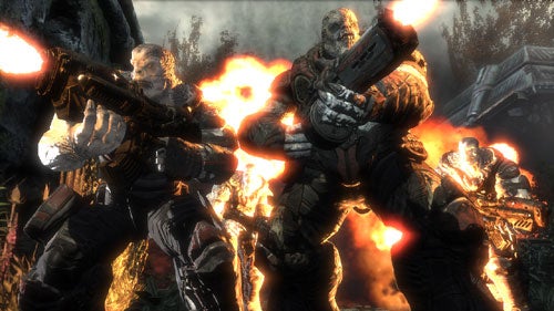 In-game screenshot showing three characters from Gears of War armed and ready for battle, with an explosion in the background.