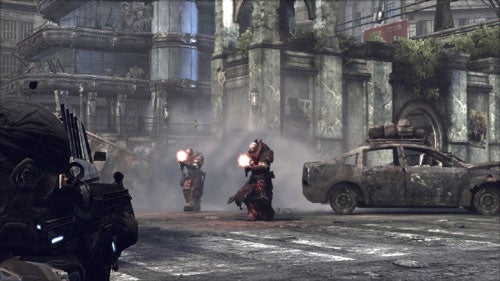 Screenshot from the 'Gears of War' video game showing a character taking cover with a gun as enemy creatures approach amidst a destroyed urban environment.