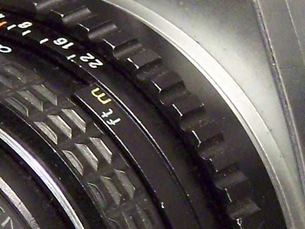 Close-up of the lens barrel of the Kodak EasyShare Z710 camera, showing the focus ring with printed distance measurements.