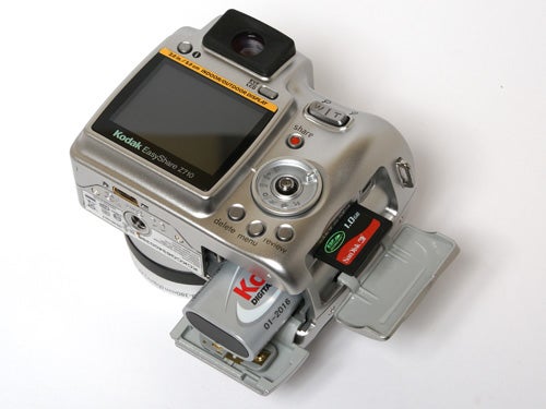 Kodak EasyShare Z710 digital camera with open card and battery compartment displaying a KODAK memory card and a battery.