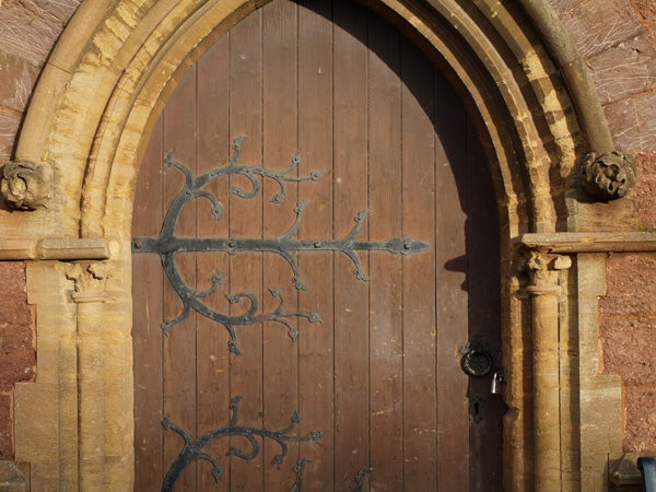 Old wooden church door with ornate iron hinges, demonstrating the image quality of the Olympus E-400 DSLR camera.