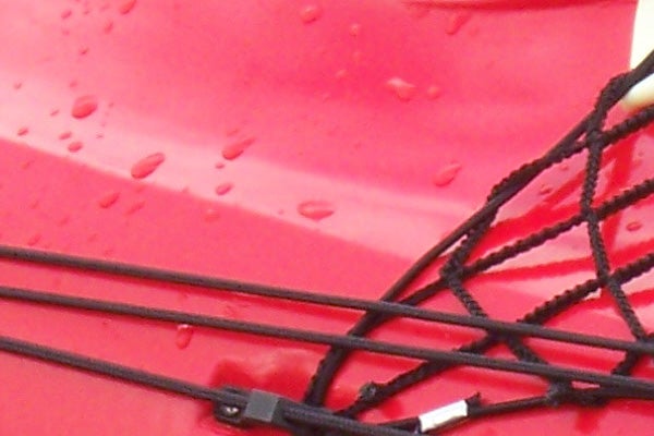 Close-up of water droplets on a glossy red surface with black netting and cord details