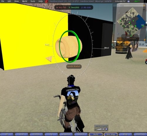 A screenshot from the virtual world Second Life showing an avatar standing before a large portal-like circular structure with a yellow frame, within a sparsely decorated area featuring geometric shapes and navigation markers.
