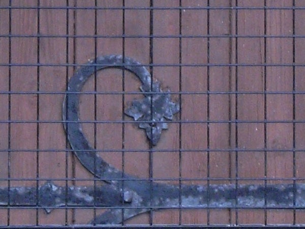 Wrought iron decorative element with maple leaf design on a brick wall, photo taken by Ricoh Caplio R5 showing camera's detail capture capability.