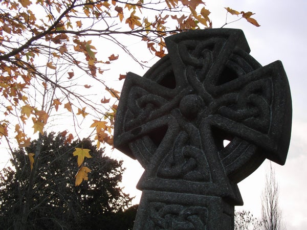 Photograph of a Celtic cross with autumn leaves in the background, demonstrating the image quality of the Ricoh Caplio R5 digital camera.