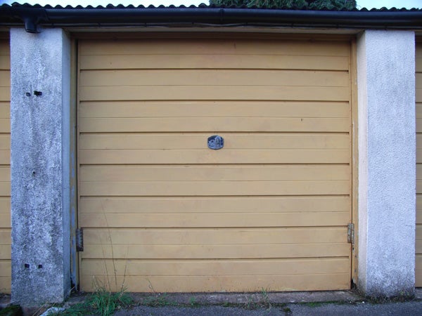 Image of a yellow garage door with a visible lion head door knocker in the center.