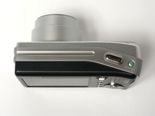 Ricoh Caplio R5 digital camera lying on a flat surface, showcasing its lens barrel, power button, and top control interface.