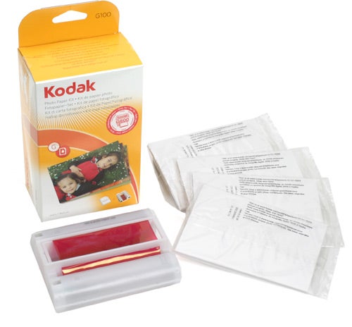 Kodak G600 Printer Dock color cartridge and photo paper refill kit displayed with its packaging box, cartridge, and several sheets of photo paper.