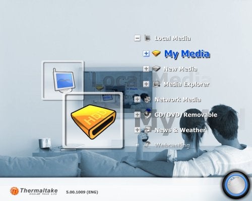 A man sitting on a couch using a remote to interact with a graphical user interface displayed on a wall, which is part of the Thermaltake Media LAB system. The interface includes options for local media, my media, media explorer, network media, and more.