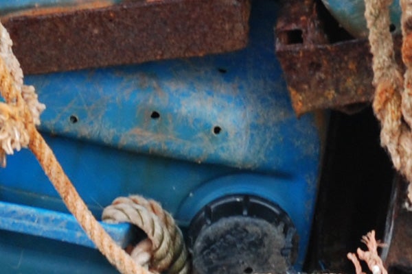 Close-up of rusty and weathered marine equipment with blue elements and coiled rope, showcasing the Nikon D80’s color detail in a textured environment.
