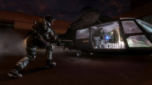 A screenshot from Tom Clancy's Rainbow Six: Vegas video game showing a soldier in tactical gear approaching a helicopter with another soldier visible inside, both ready for a mission, set in a dimly lit urban environment at night.