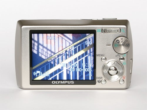 Olympus mju 1000 10MP compact camera displayed on a white background, with its large LCD screen on the back showing a photographed image with visible on-screen settings and information.