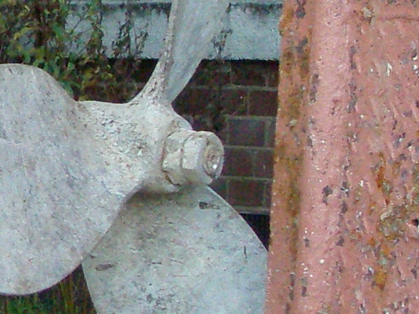 The image shows a close-up of a weathered boat propeller next to a brick structure, demonstrating the level of detail captured by the Olympus mju 1000 10MP Compact Camera.