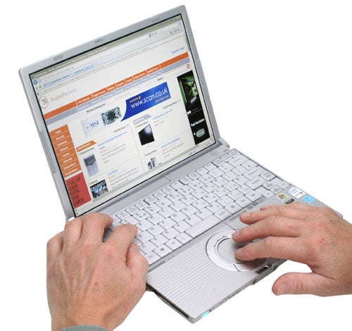 Person using a Panasonic ToughBook CF-W5 laptop displaying a webpage with visible keyboard and trackpad.