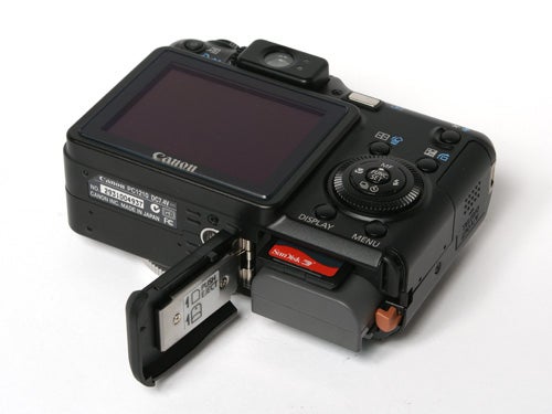 Canon PowerShot G7 digital camera with an open battery compartment displaying the battery and memory card slots.