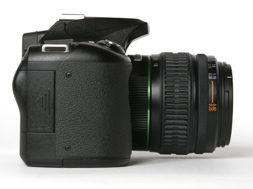 Pentax K100D Digital SLR camera with a lens attached, viewed from the side against a white background.