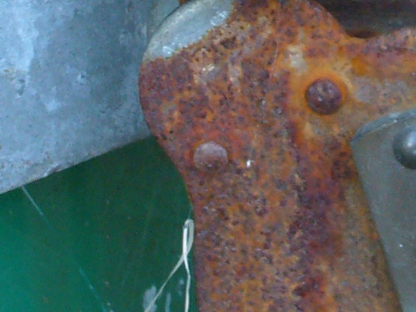 Close-up of a rusty metal surface with two bolts, highlighting texture details and color variations.
