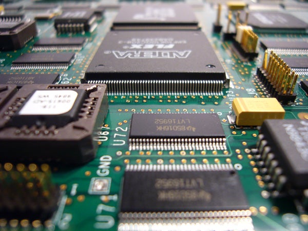 Close-up of a green printed circuit board with microchips and electronic components, potentially from a digital camera like the Panasonic Lumix DMC-FX01.