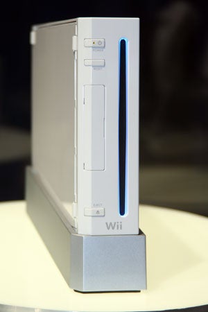 Nintendo Wii console standing vertically on its stand with the power indicator glowing blue.