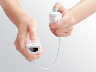 Close-up of two hands holding a white Nintendo Wii Nunchuk controller and connecting it to a Wii Remote against a neutral background.