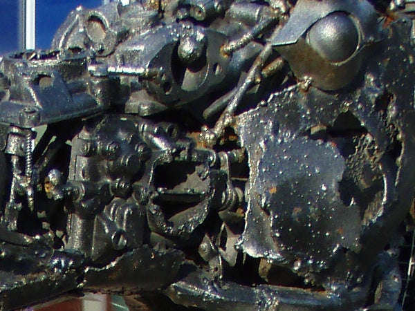Close-up view of a heavily damaged Olympus mju 725 SW camera, showcasing the camera's rugged build and damage resistance.