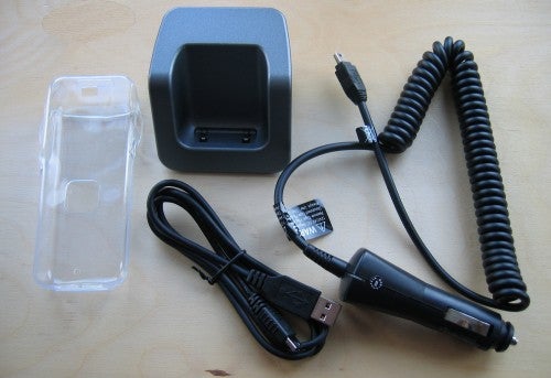 O2 Jet product with accessories displayed on a wooden surface, including a charging cradle, a clear plastic case, USB cable, and car charger.