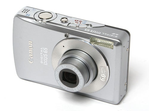 Silver Canon Digital IXUS 65 compact camera with lens extended on a white background.