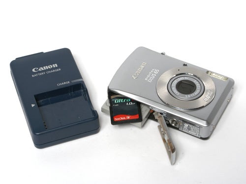 Canon Digital IXUS 65 camera with battery charger, memory card, and battery displayed on a white background.