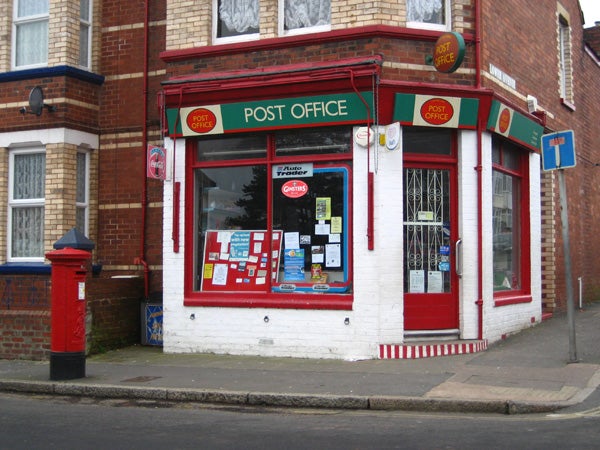 This image shows a traditional British post office storefront with a bright red postbox outside, possibly taken with a Canon Digital IXUS 65 camera demonstrating its color capture and clarity in daylight conditions.