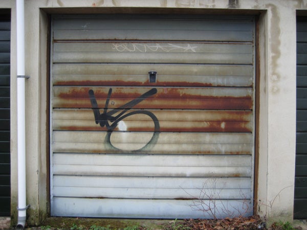 Corroded metal garage door with graffiti.