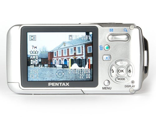 Pentax W20 waterproof camera displayed with its LCD screen showing a photo of a building exterior.