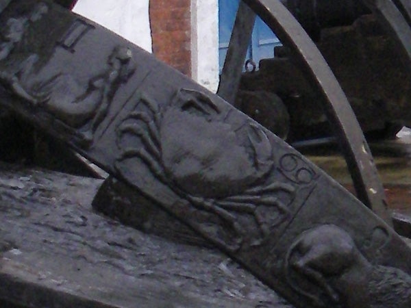 Close-up image of a weathered cannon with intricate designs, possibly from a historical ship or fortification.