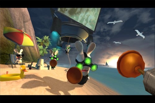 Screenshot from the video game Rayman Raving Rabbids showing a beach setting with several Rabbids engaging in comedic activities, one flying towards the screen with plungers as hands, others lounging and sunbathing, with seagulls and a blimp in the background.