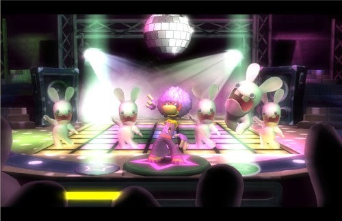 Image from the video game Rayman Raving Rabbids showing animated rabbids characters dancing on a disco floor with a disco ball overhead, as part of a mini-game, with an audience of rabbids in the foreground.