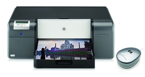HP Photosmart Pro B9180 printer with a printed photo of a landscape featuring buildings reflecting on water, alongside its gray-colored calibration device.